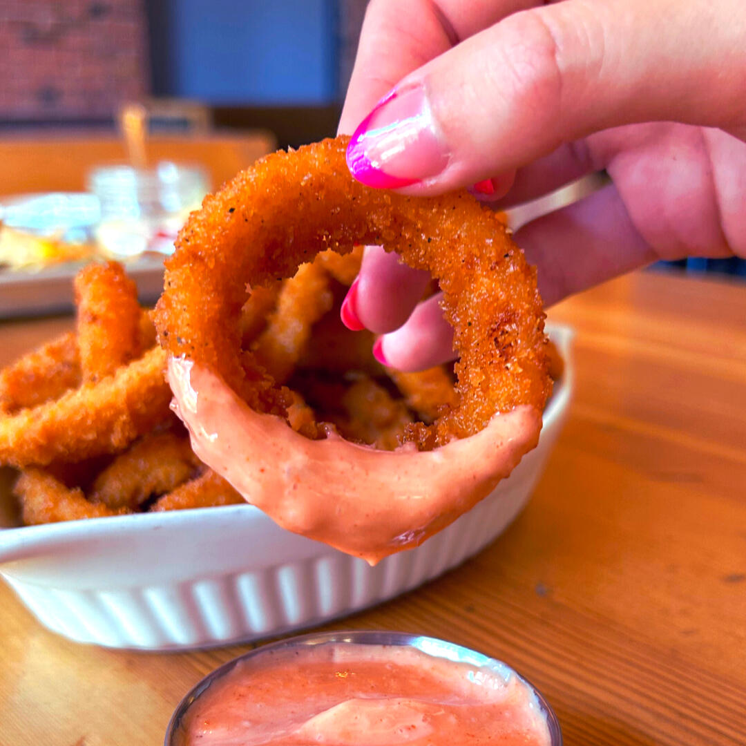 Golden crispy onion rings served at Swans Pub for Happy Hour daily from 3pm to 6pm in Victoria, BC. Perfect for sharing with friends.